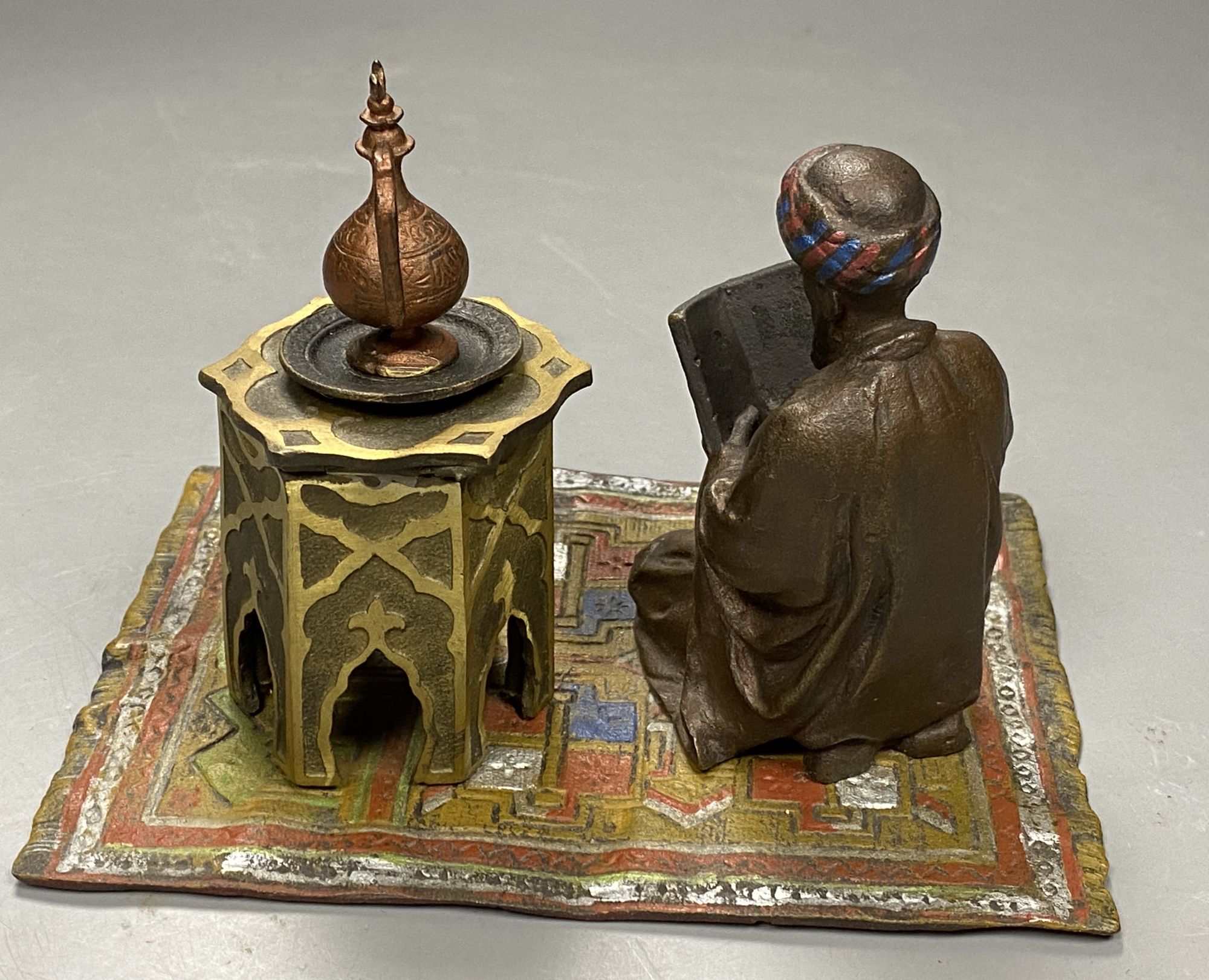 A cold painted bronze desk stand modelled as a reading Arab, length 14.5cm